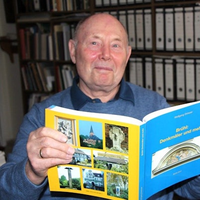 Zu sehen ist Wolfgang Drösser, der eines der selbst verfassten Bücher in den Händen hält.