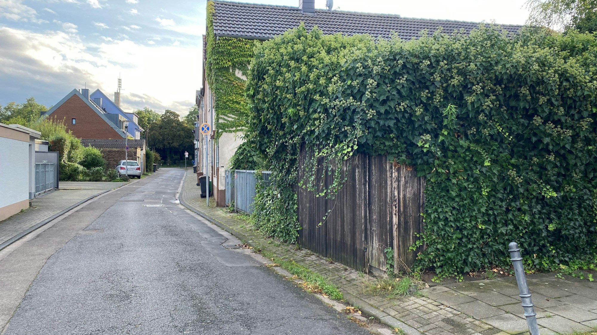 An einer schmalen Straße stehen Einfamilienhäuser und Garagen.