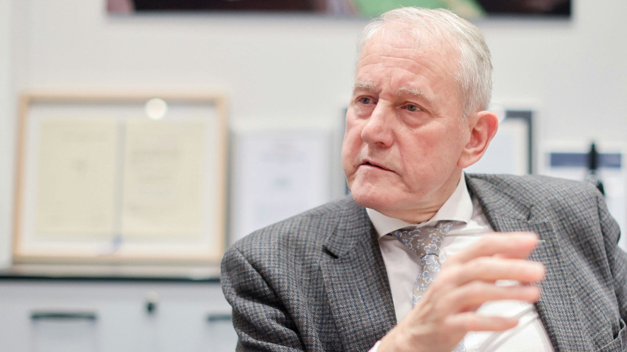 Auf dem Foto ist Louwrens Langevoort zu sehen, er trägt einen grauen Anzug mit Krawatte.