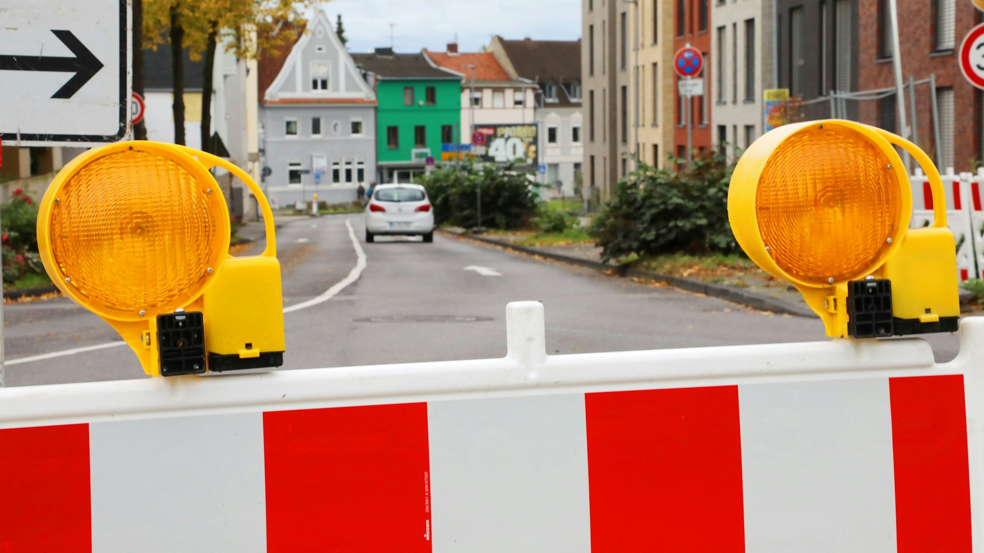 Eine Warnbake steht vor einer Straße im Hintergrund ist ein Auto zu sehen.