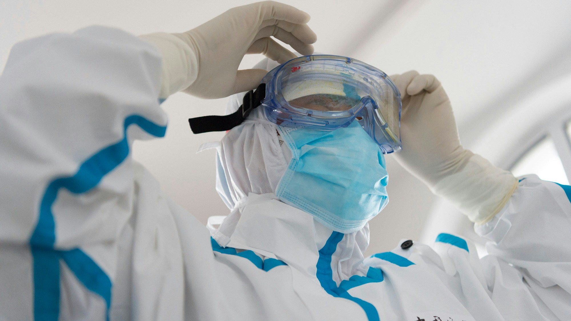 Ein Mitarbeiter des Gesundheitswesens legt im Hafen von Fuyuan seine Schutzkleidung an.