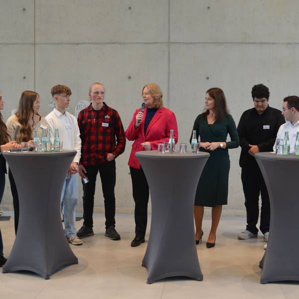 Bundestagspräsidentin Bärbel Bas mit Schülern an Stehpulten.