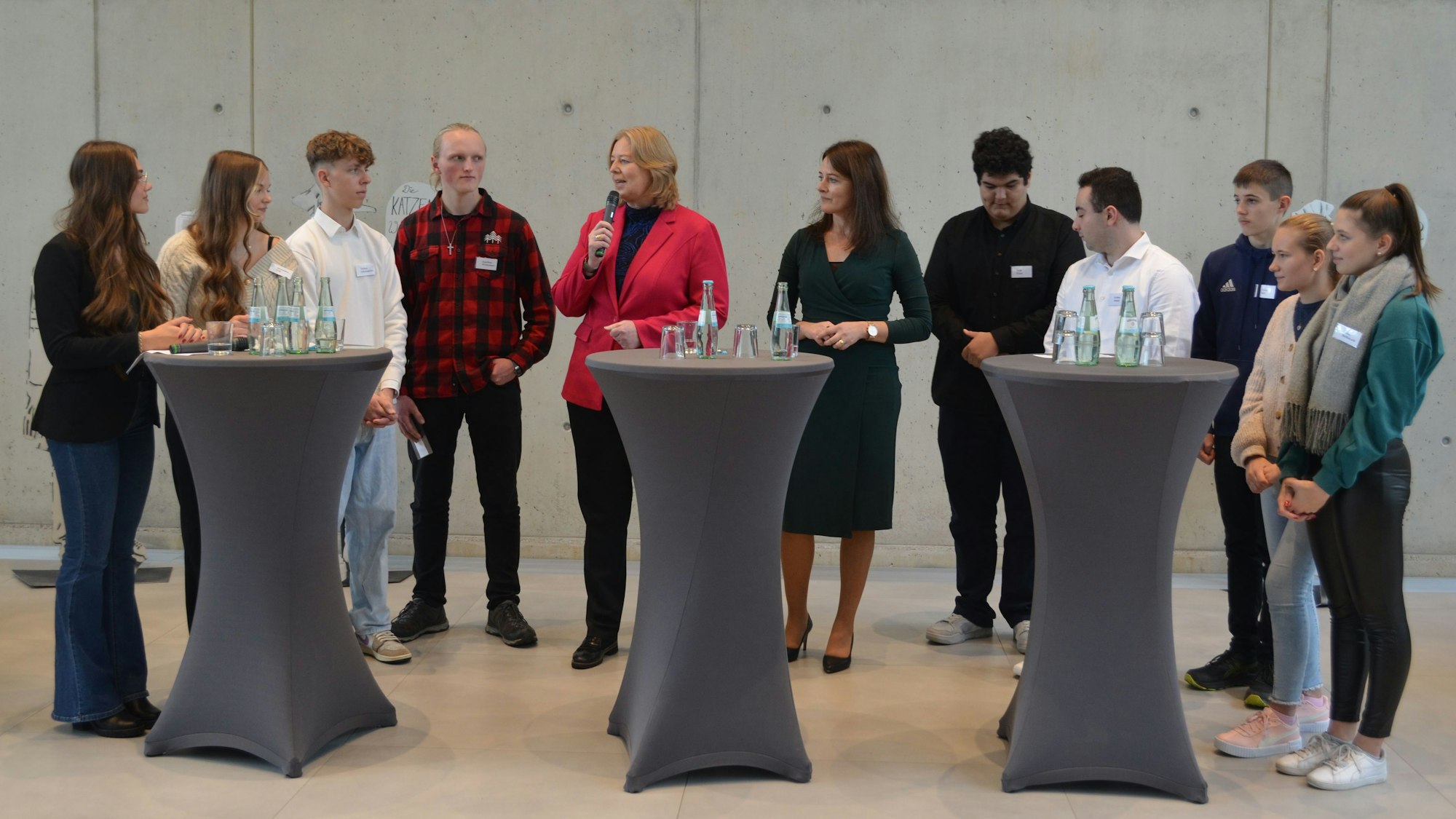 Bundestagspräsidentin Bärbel Bas mit Schülern an Stehpulten.