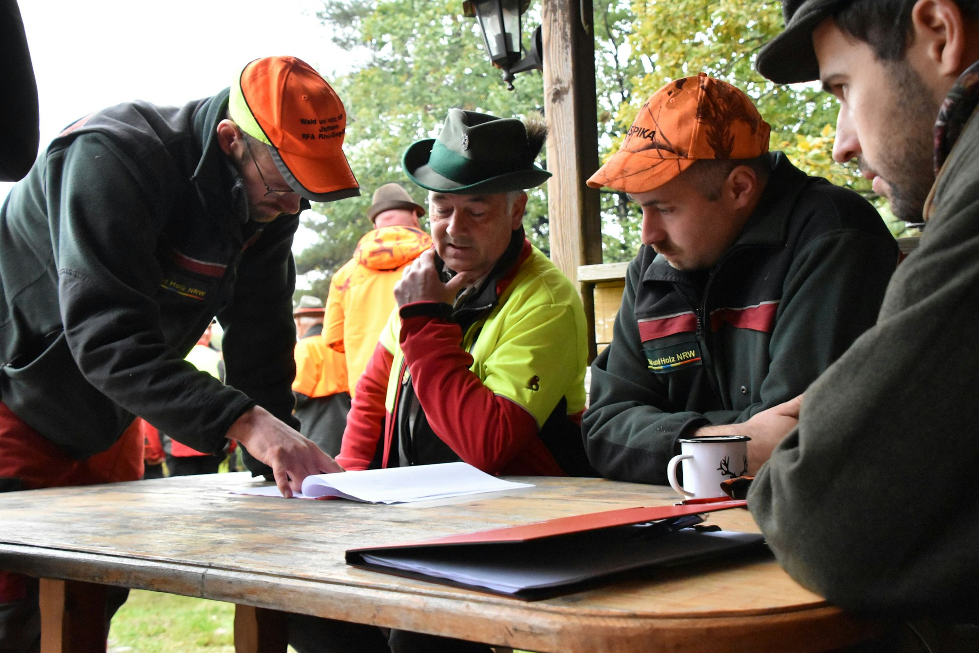 Vier Förster sitzen um einen Tisch und studieren Papiere.