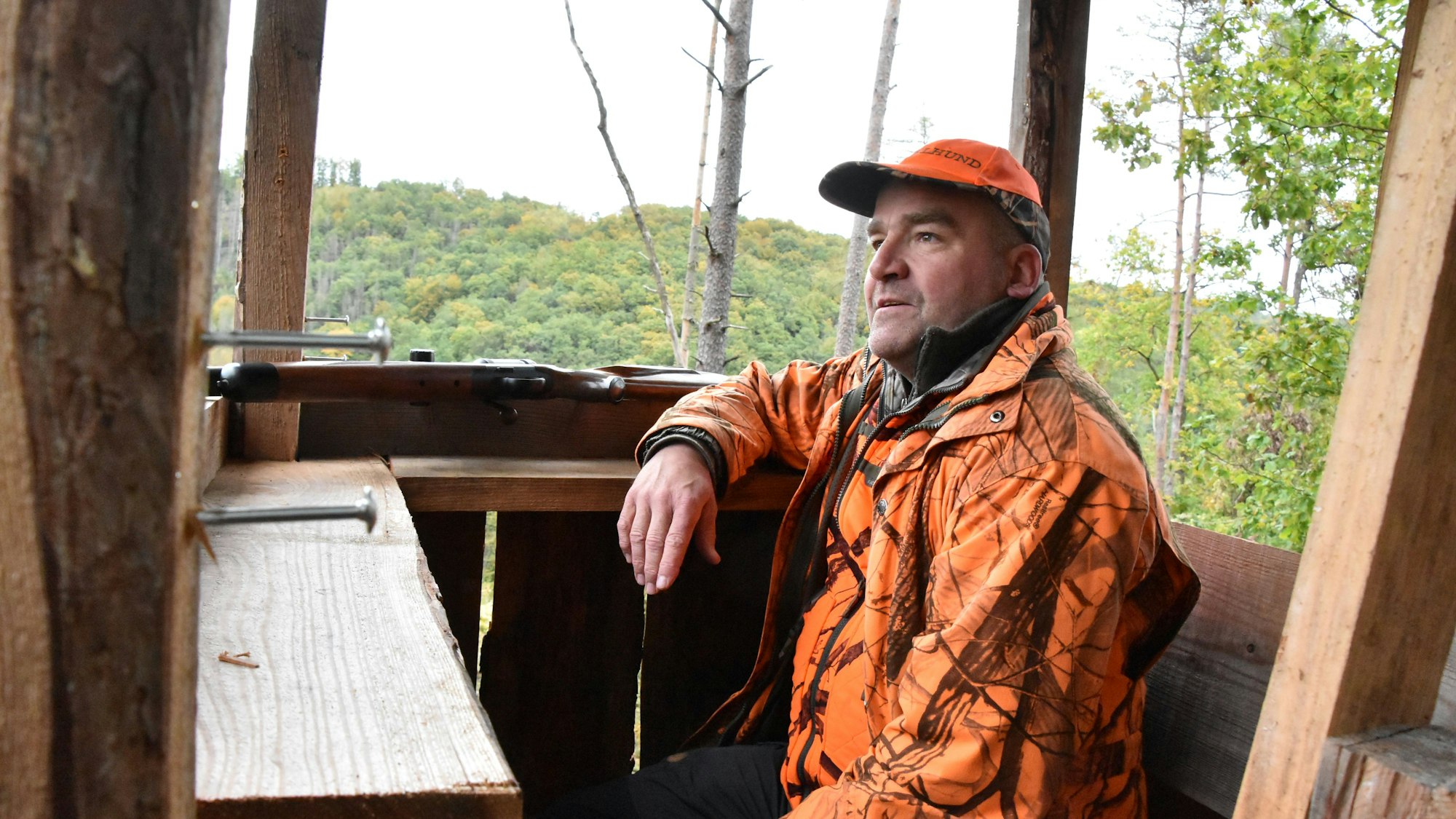 Der Jäger sitzt auf dem Hochsitz und schaut in die Ferne.