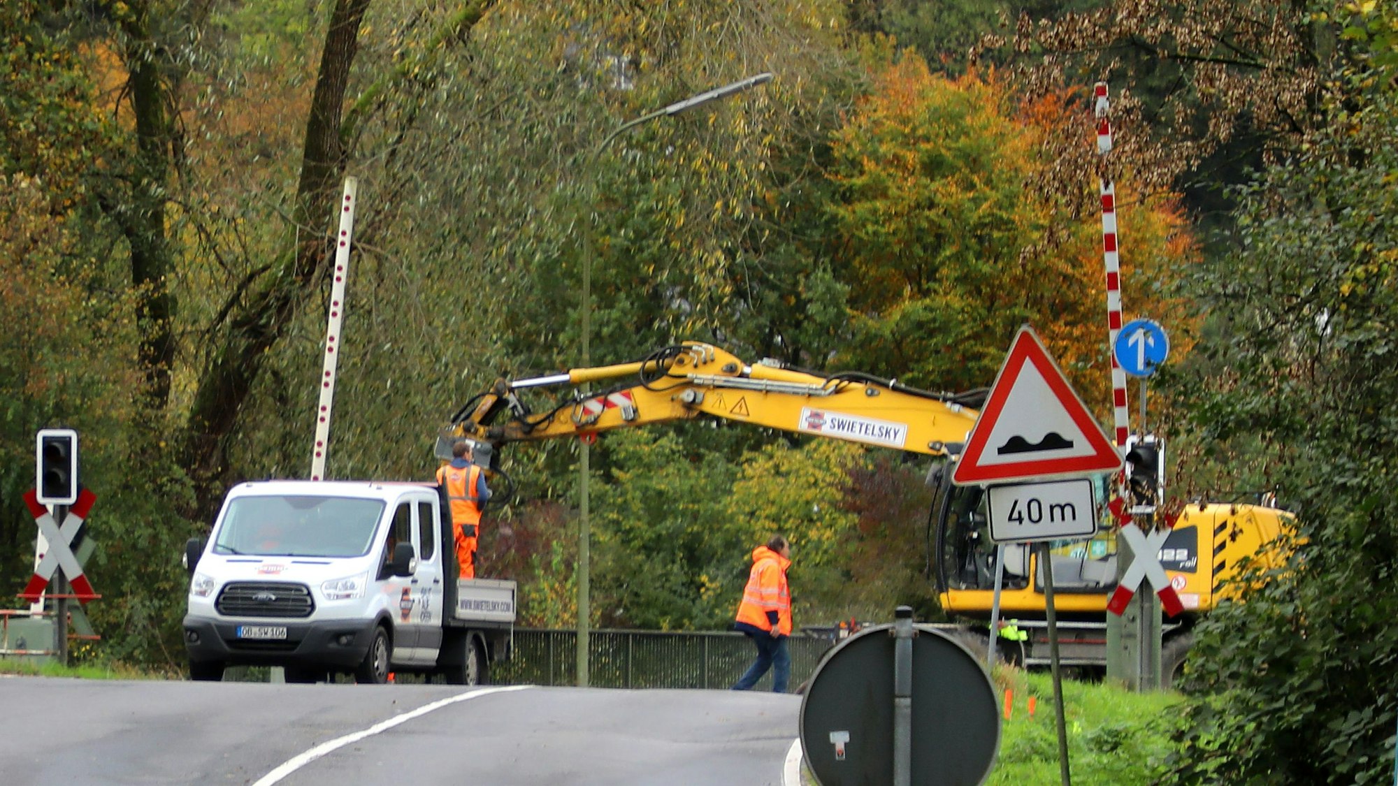 Ein Schienenbagger steht auf dem Bahnübergang der Mucher Straße in Overath.