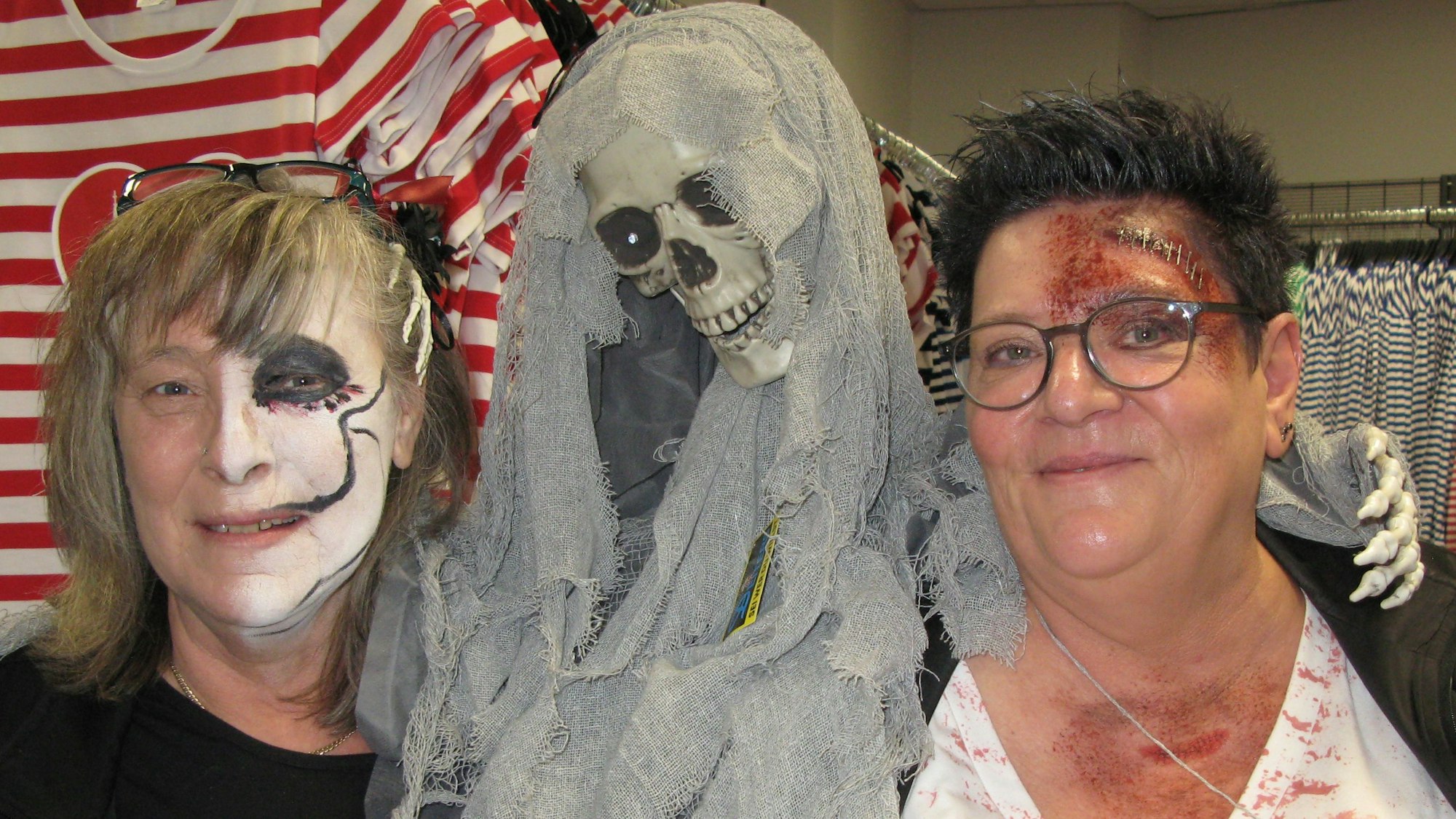Das Bild zeigt zwei Frauen im Kostümgeschäft Deiters mit einem Skelett und zum Gruseln geschminkten Gesichtern.
