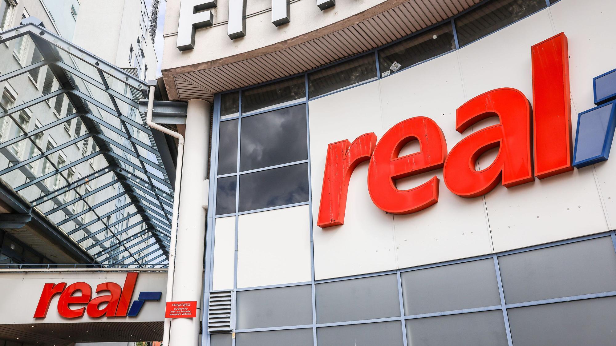 29.09.2023, Nordrhein-Westfalen, Köln: Logos hängen über dem Eingang eines Real Marktes. Die SB-Warenhauskette Mein Real hat nach eigenen Angaben einen Antrag auf Eröffnung eines Insolvenzverfahrens in Eigenverwaltung gestellt. (zu dpa ·Mein Real stellt Antrag auf Insolvenz in Eigenverwaltung·) Foto: Oliver Berg/dpa +++ dpa-Bildfunk +++