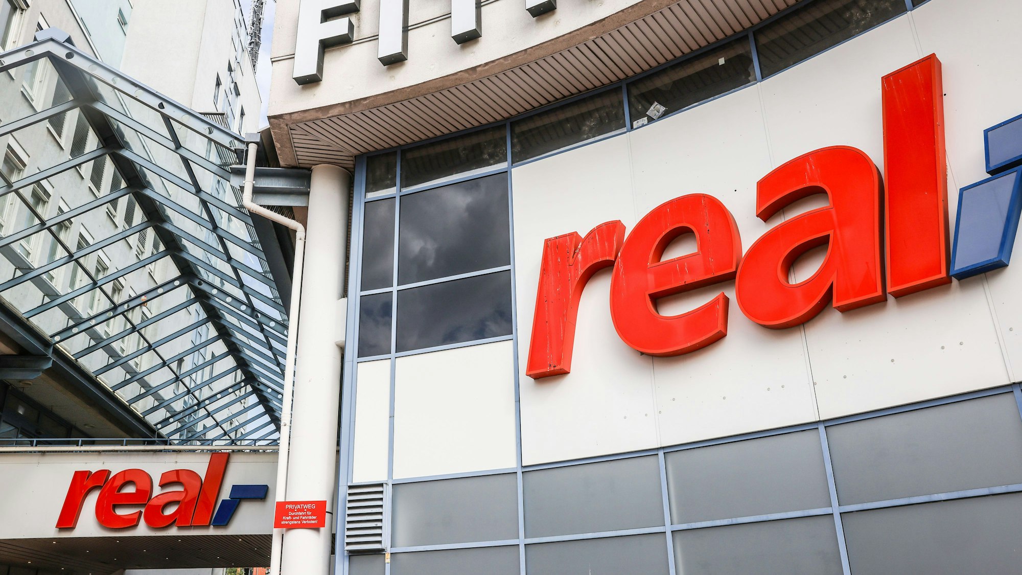 29.09.2023, Nordrhein-Westfalen, Köln: Logos hängen über dem Eingang eines Real Marktes. Die SB-Warenhauskette Mein Real hat nach eigenen Angaben einen Antrag auf Eröffnung eines Insolvenzverfahrens in Eigenverwaltung gestellt. (zu dpa ·Mein Real stellt Antrag auf Insolvenz in Eigenverwaltung·) Foto: Oliver Berg/dpa +++ dpa-Bildfunk +++