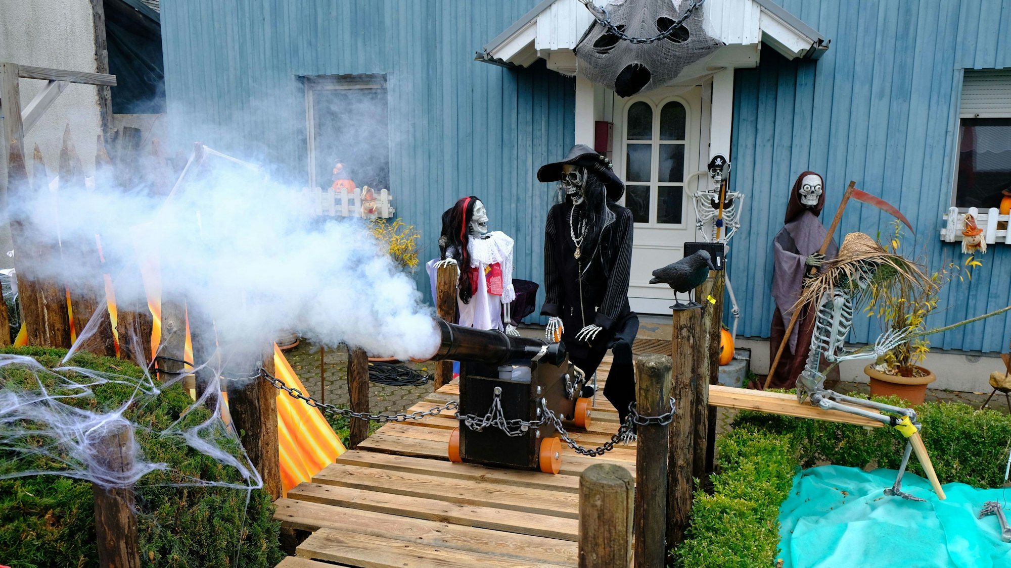 Das Haus mit seiner blauen Holzfassade ist zu Halloween mit allerlei Skeletten im Piraten-Look dekoriert. Aus dem Rohr einer Kanone quillt Rauch.