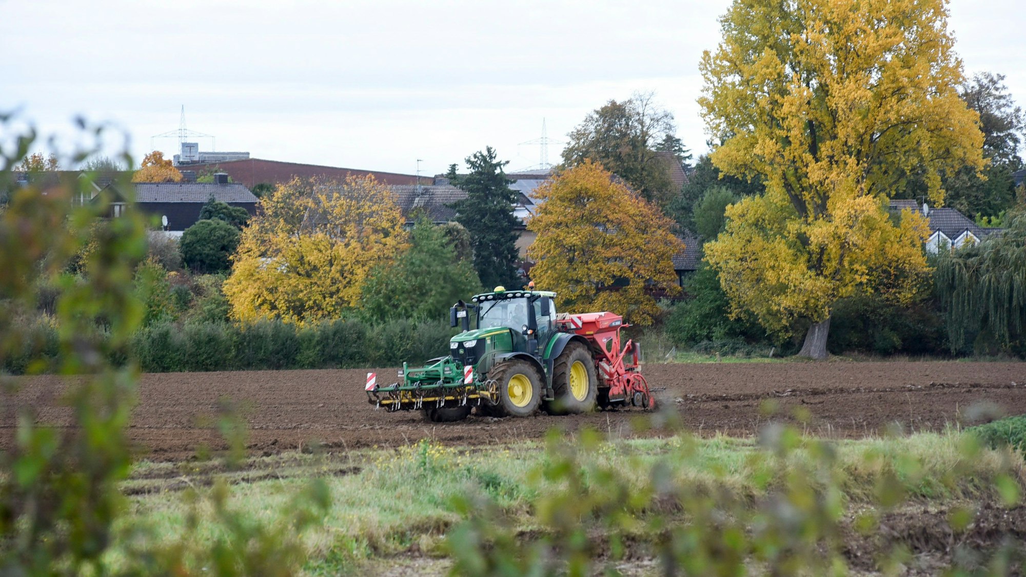 Auf dem Foto ist ein Traktor auf dem Feld bei der Aussaat zu sehen.