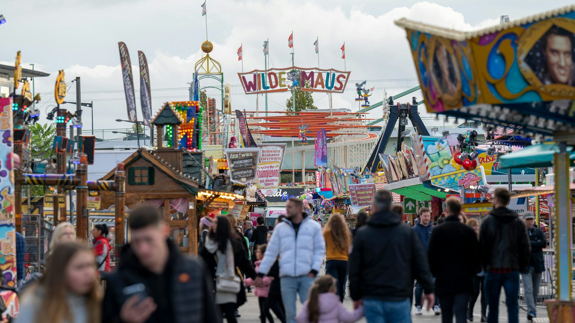 Besucherinnen und Besucher schlendern über den Rummelplatz.