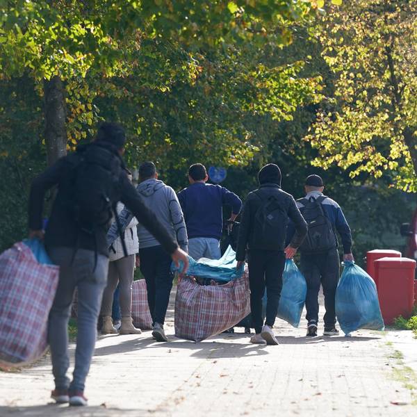 Flüchtlinge gehen mit ihrem Gepäck zu der Flüchtlingsunterkunft.