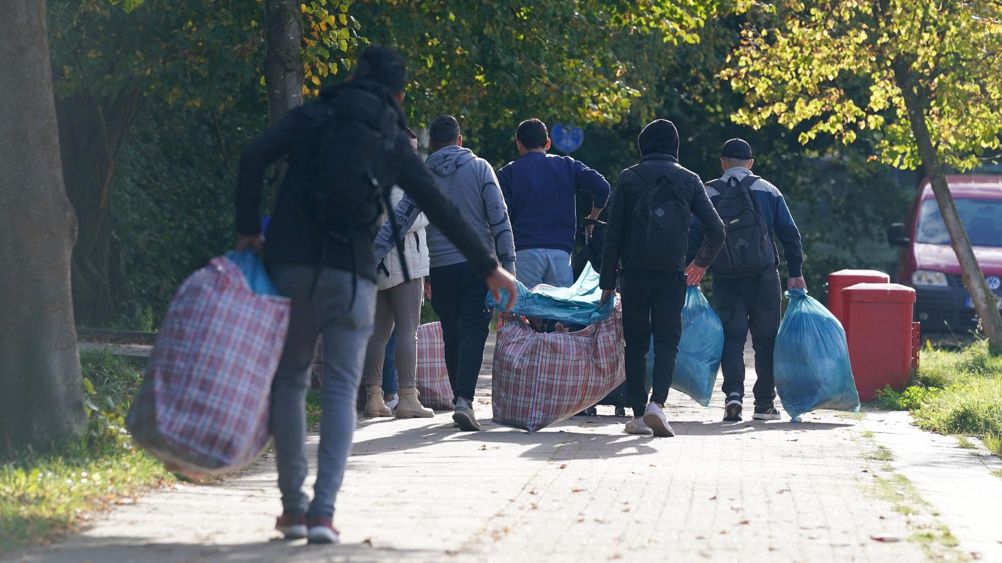 Flüchtlinge gehen mit ihrem Gepäck zu der Flüchtlingsunterkunft.