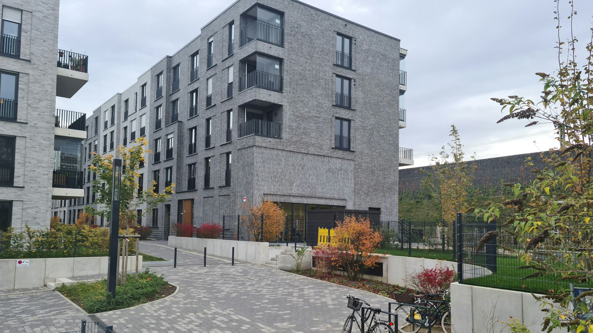 Zwei neue mehrstöckige Wohnblöcke stehen hinter einer Lärmschutzwand.