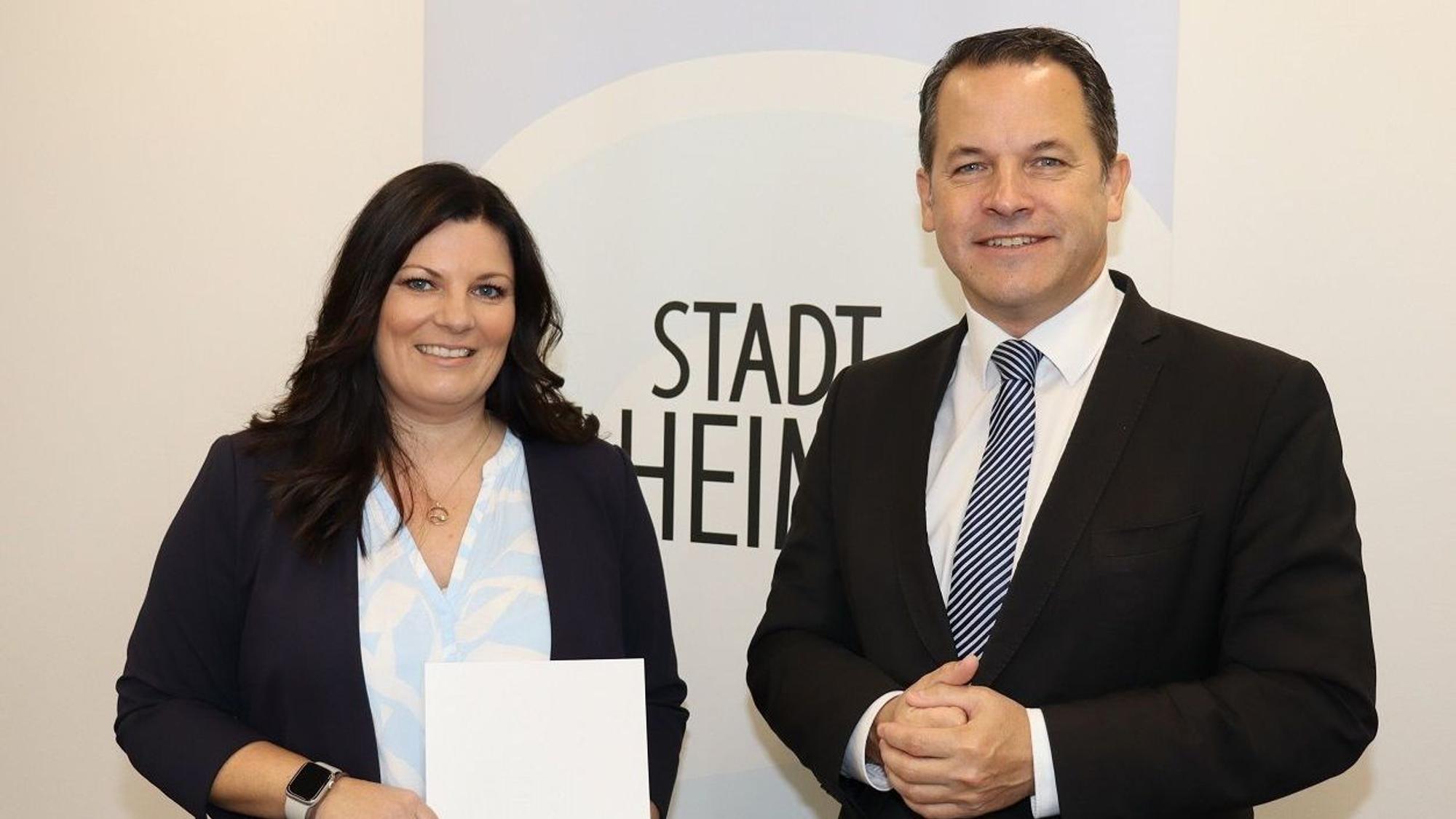 Die Dezernentin und der Bürgermeister strahlen, sie hält eine Urkunde in der Hand.
