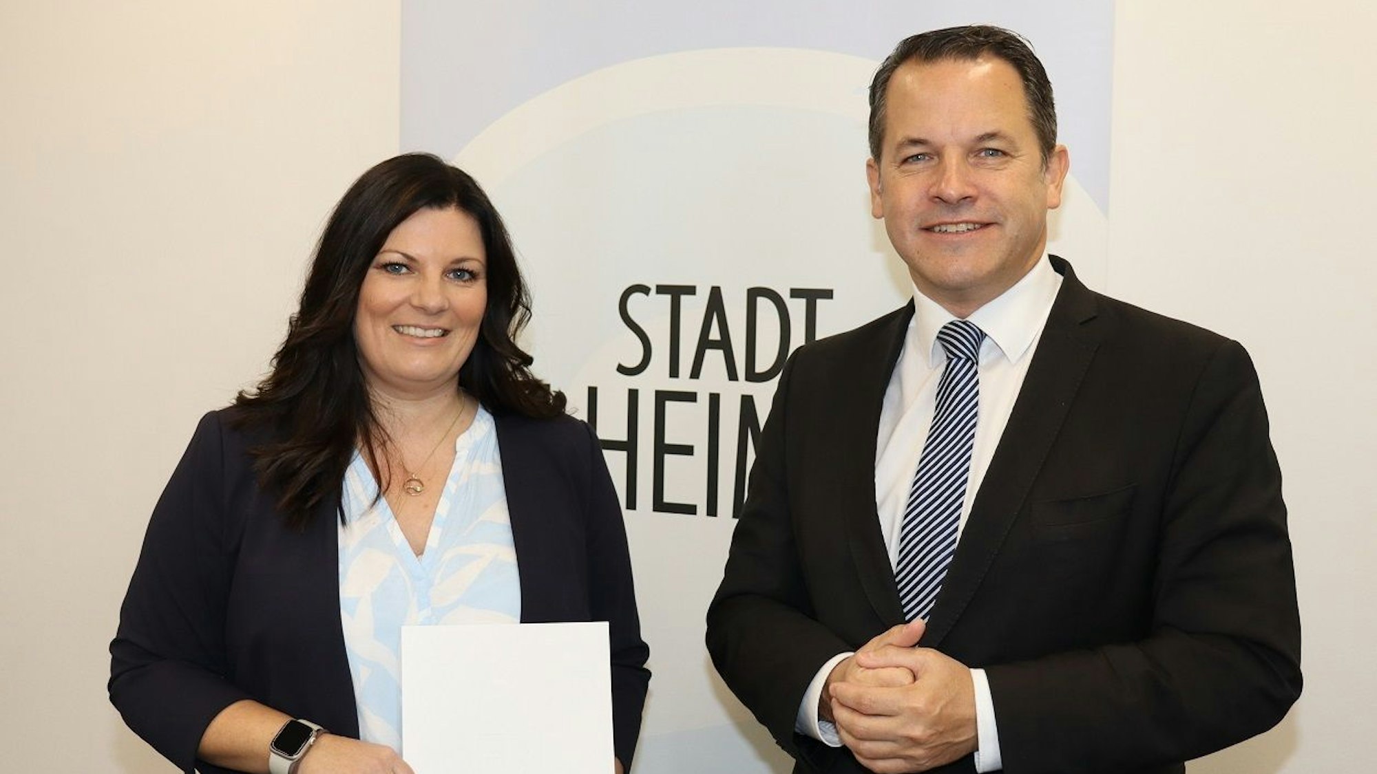 Die Dezernentin und der Bürgermeister strahlen, sie hält eine Urkunde in der Hand.