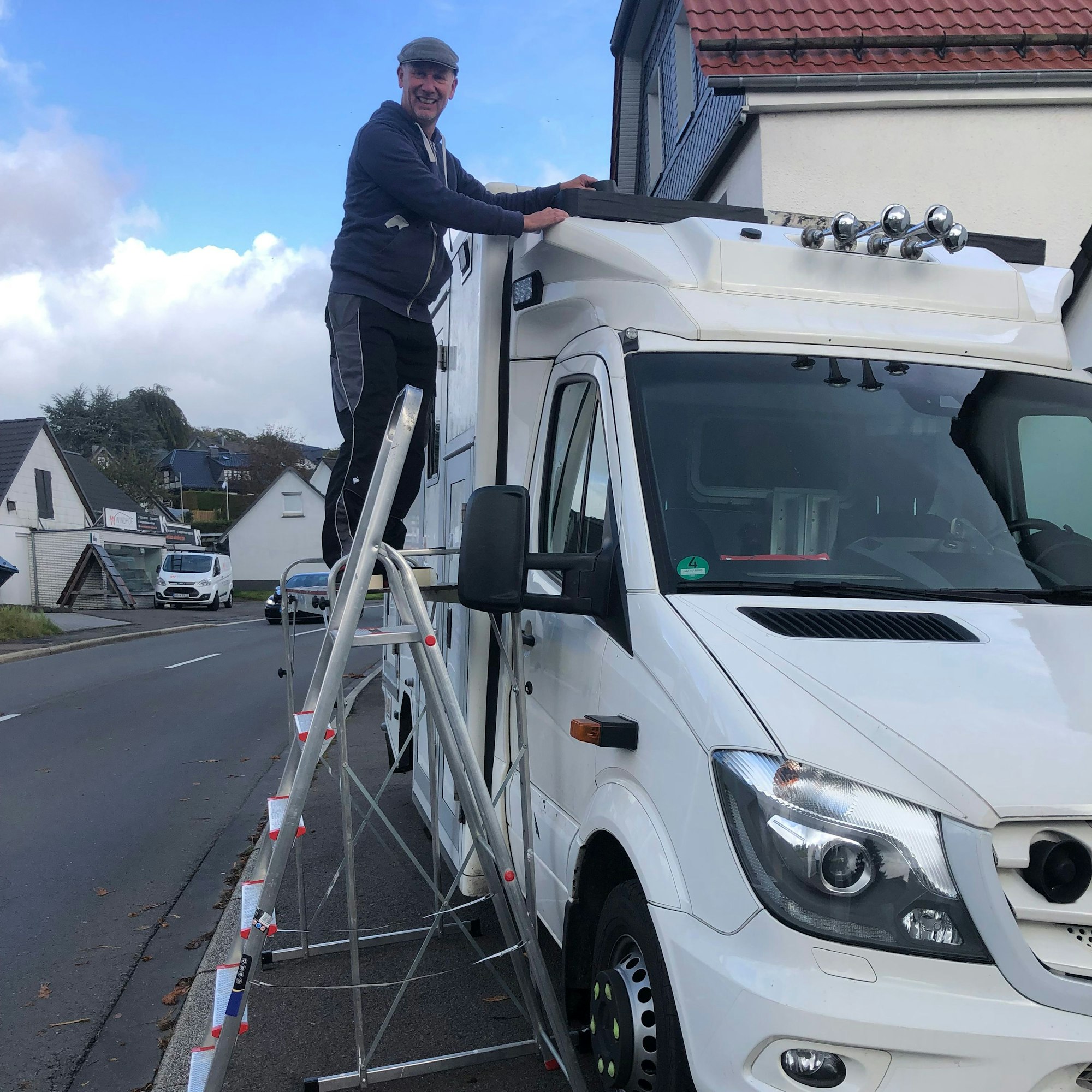 Ein Mann steht auf einer Leiter und bereitet einen Krankenwagen vor.
