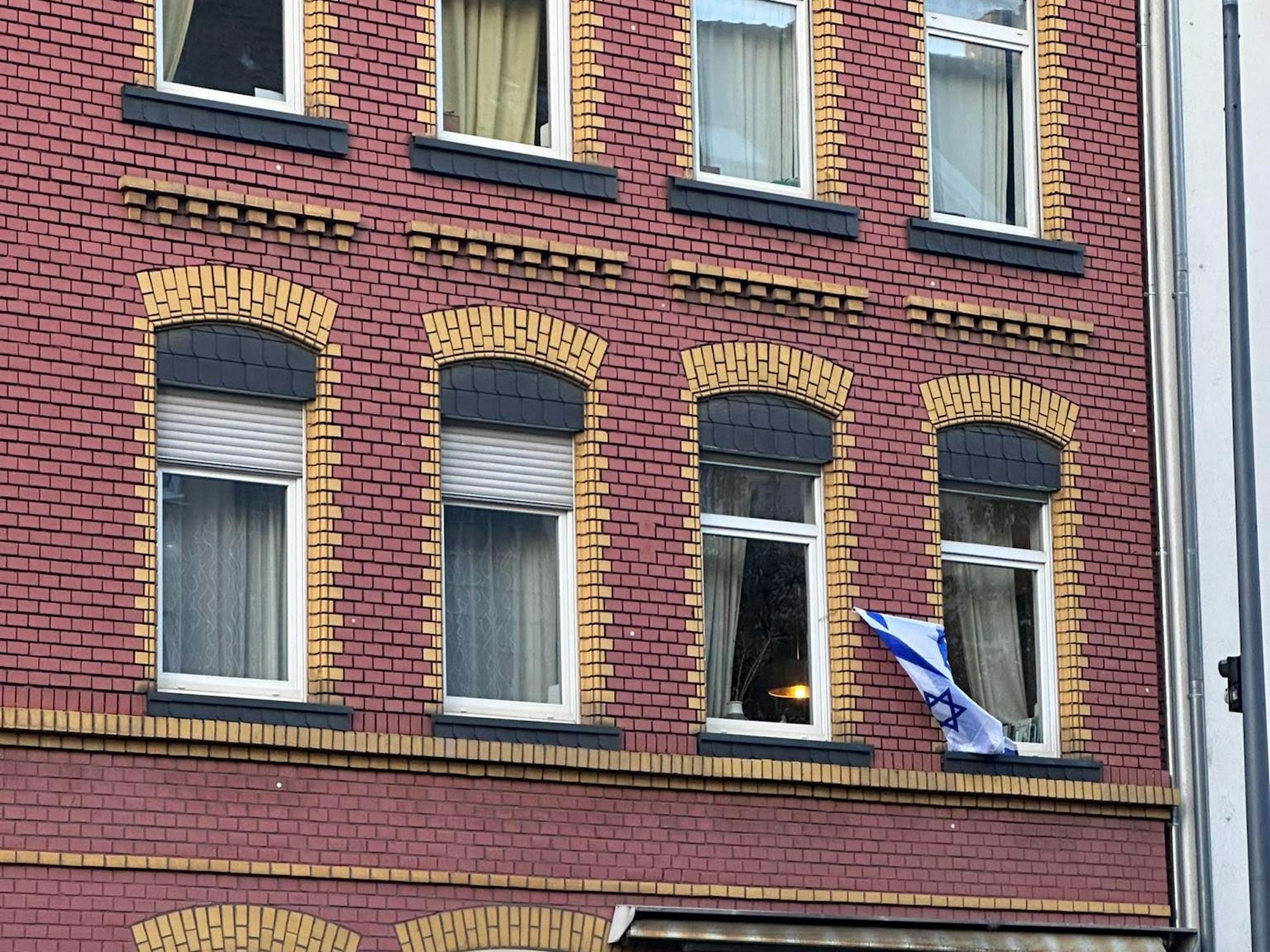 Israel-Flagge an einer Hausfassade zwischen zwei Fenstern