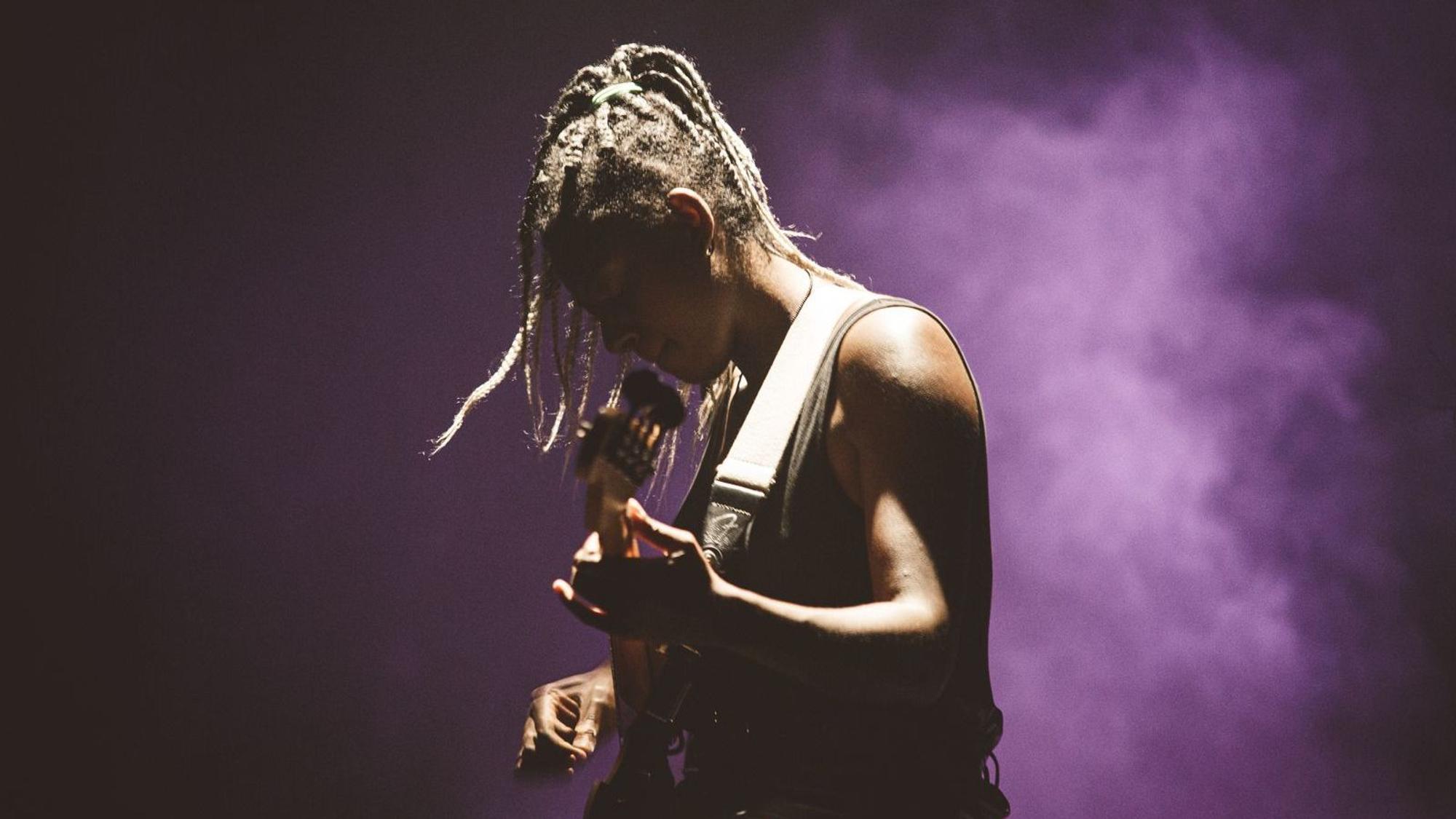 Farida Amadou spielt Bass auf einer Bühne.