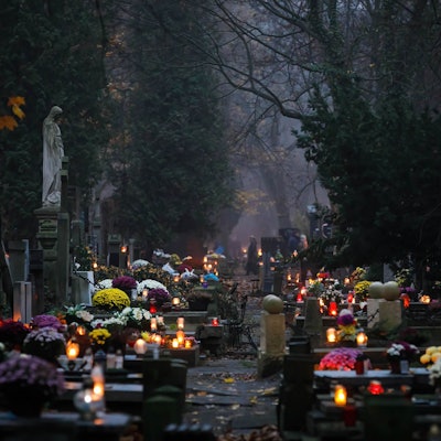 Brennenden Kerzen und Blumen schmücken eine Reihe von Gräbern.