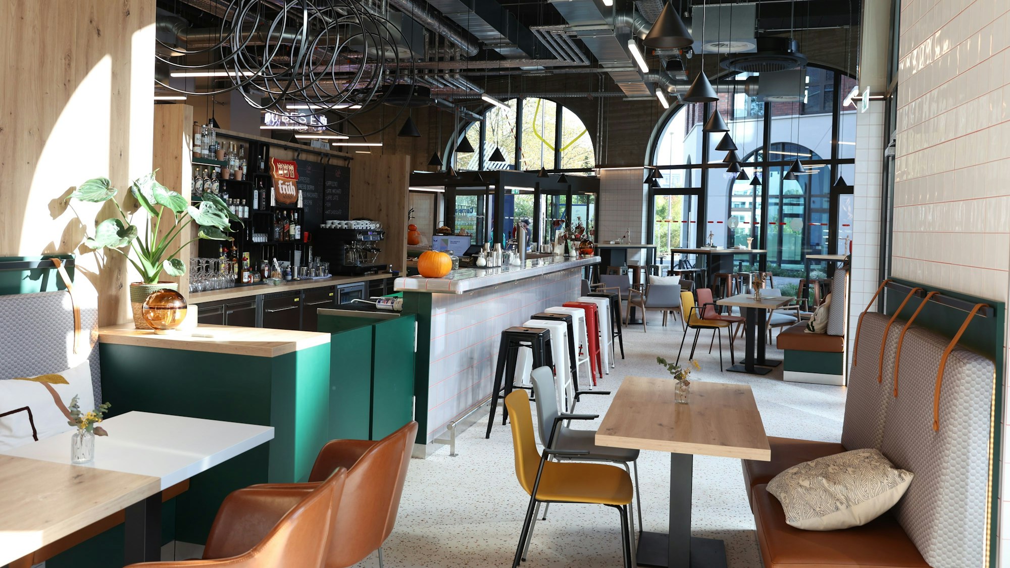 Ein heller Raum mit Tischen, Stühlen und einer Bar