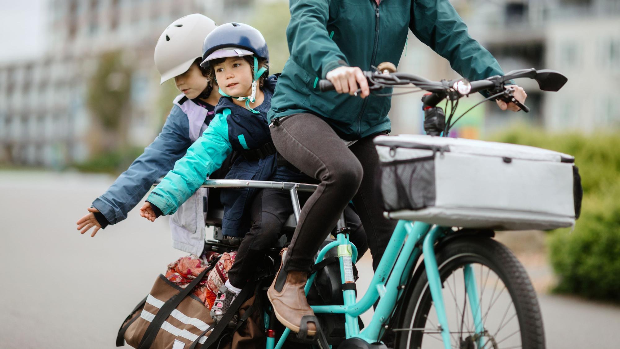 Frau fährt mit zwei Kindern auf dem Fahrrad Foto: Getty Images/RyanJLane