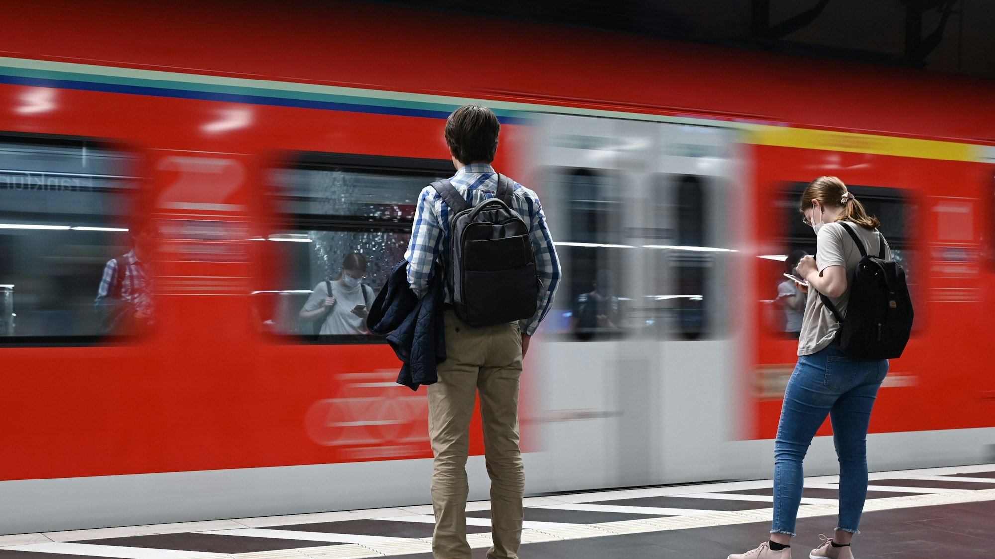 Hessen, Frankfurt/Main: Zugreisende warten im Hauptbahnhof auf die Einfahrt einer S-Bahn (Aufnahme mit länger Verschlusszeit).