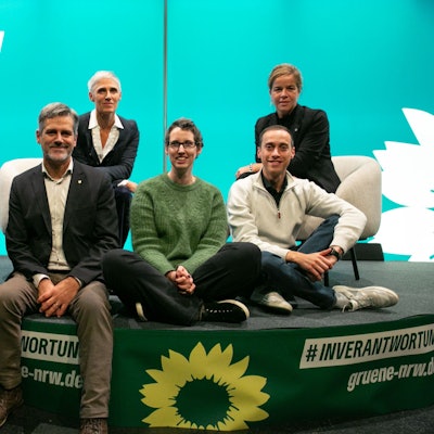 Drei Frauen und drei Männer posieren auf einem Podium.