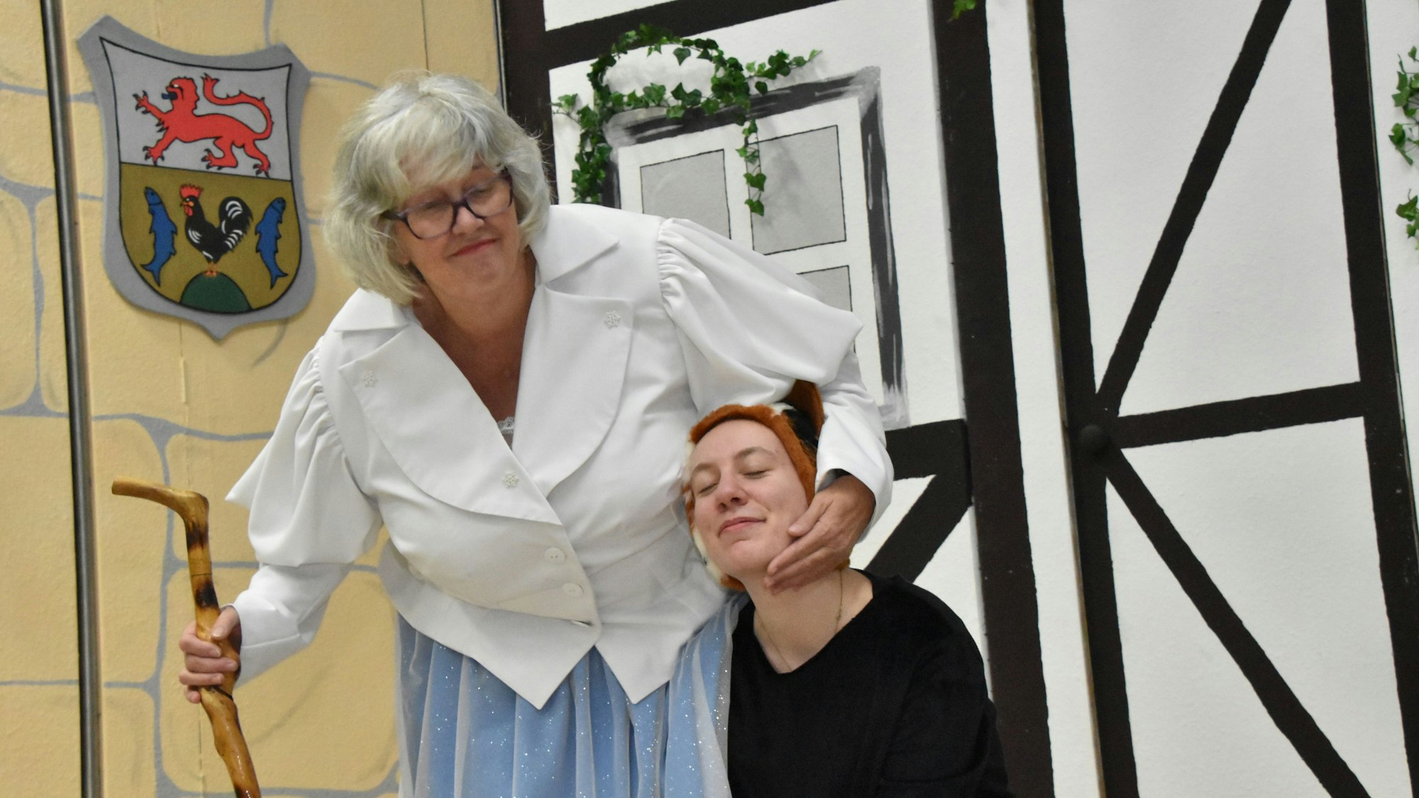 Eine ältere Dame streichelt die Katze, dargestellt von einer Mimin.