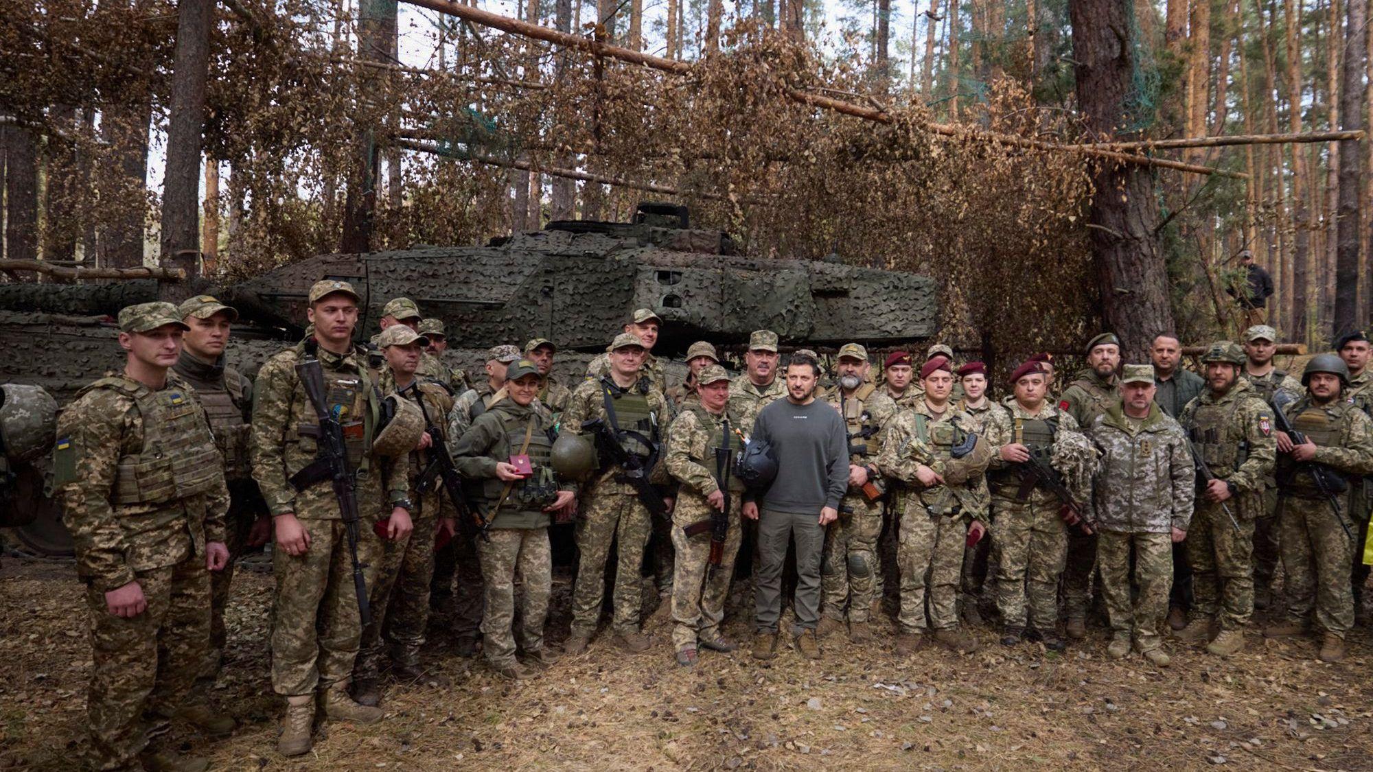 Der ukrainische Präsident Wolodymyr Selenskyj steht Anfang Oktober bei einem Frontbesuch neben ukrainischen Soldaten vor einem Leopard 2-Panzer.