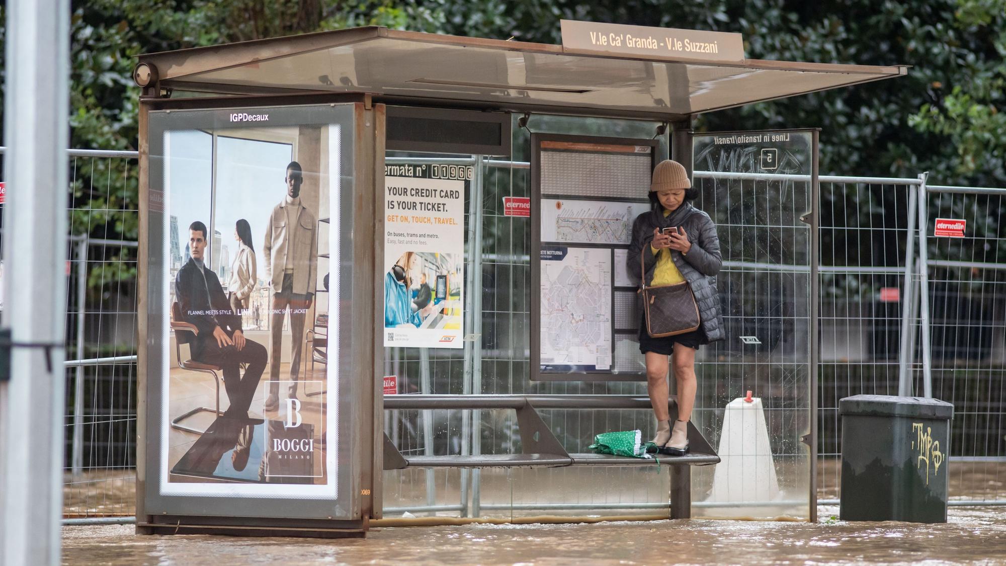 Eine Frau steht auf einer Sitzbank einer Bushaltestelle in Mailand. Die Stadt wurde nach schweren Regenfällen teilweise meterhoch überschwemmt.