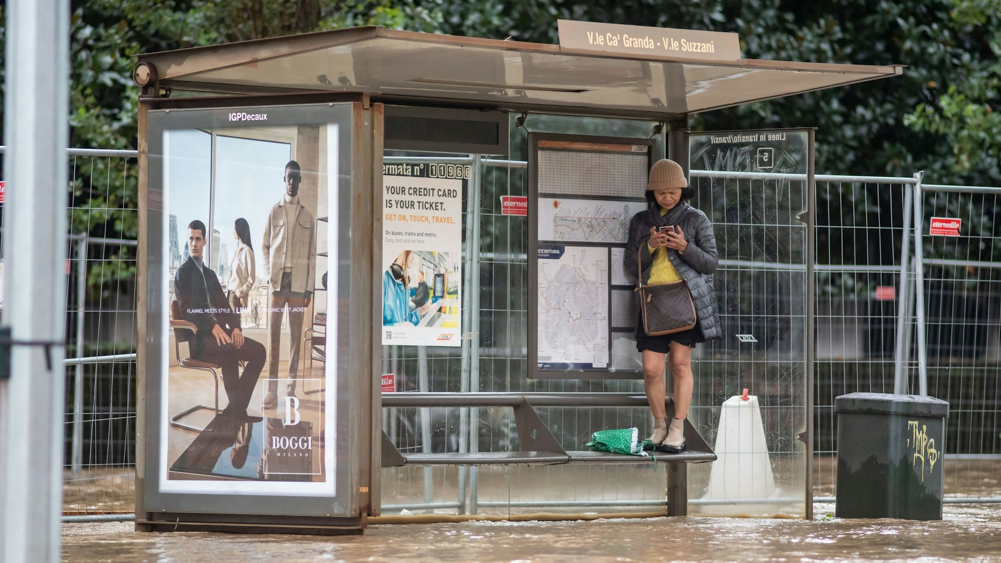 Eine Frau steht auf einer Sitzbank einer Bushaltestelle in Mailand. Die Stadt wurde nach schweren Regenfällen teilweise meterhoch überschwemmt.