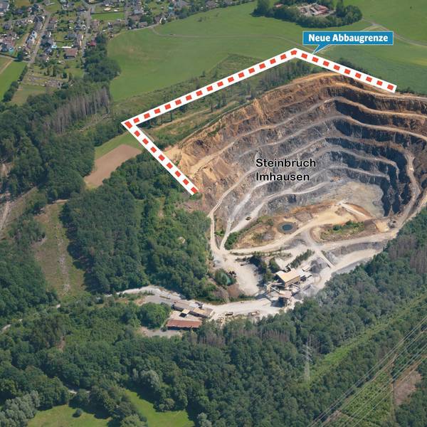 Blick aus der Vogelperspektive auf den von Wald und Wiesen umgebenen Steinbruch Imhausen und die nah gelegene Ortschaft Imhausen.
