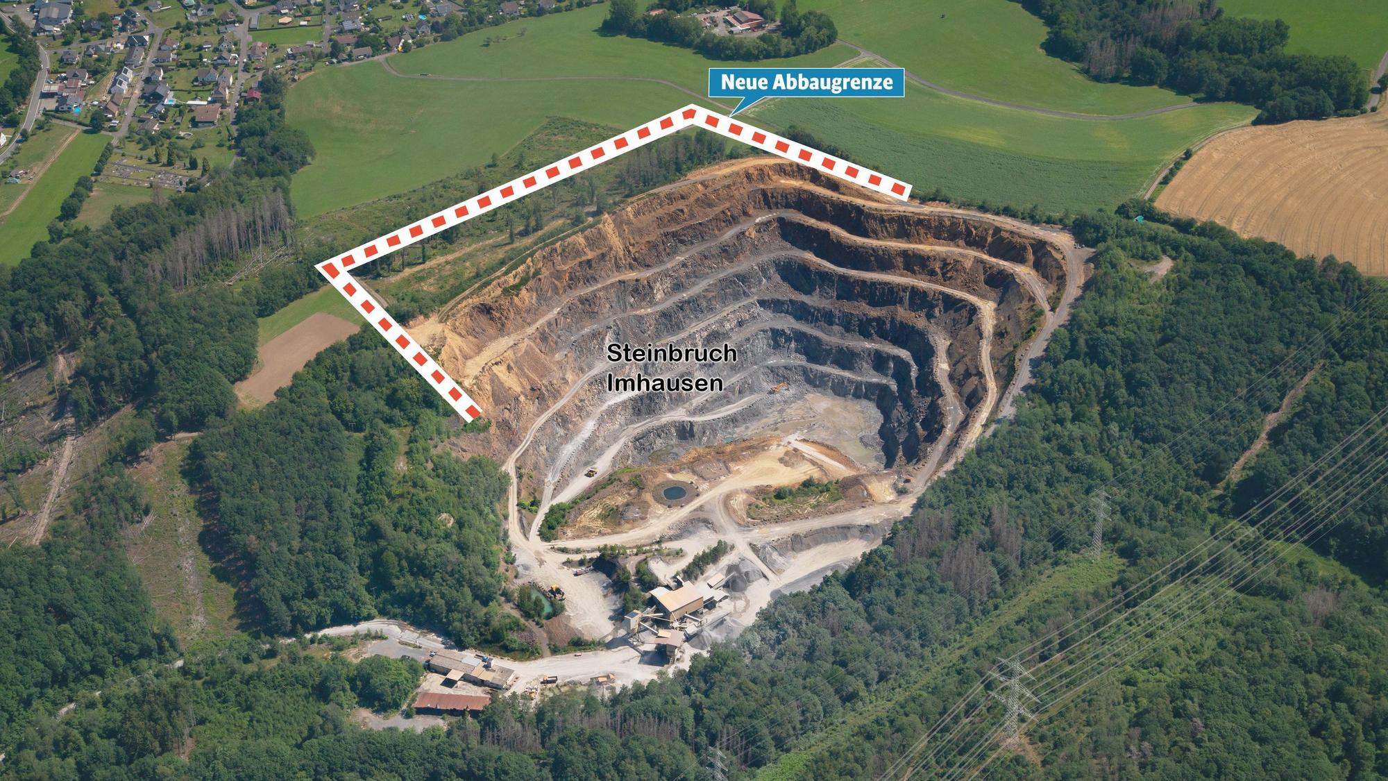 Blick aus der Vogelperspektive auf den von Wald und Wiesen umgebenen Steinbruch Imhausen und die nah gelegene Ortschaft Imhausen.