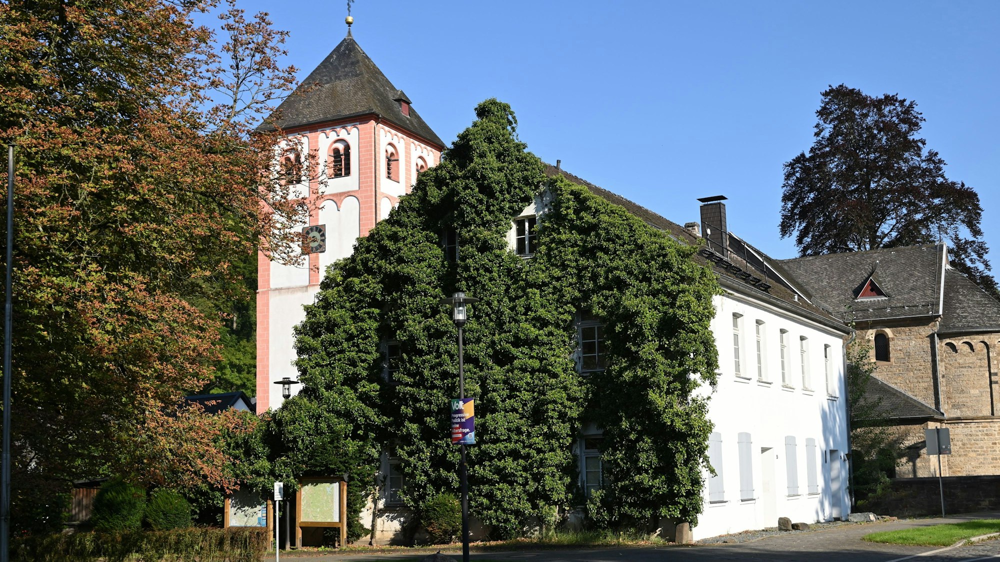 Das efeubewachsene Gebäude der Alte Kaplanei in Odenthal. Dahinter der Kirchturm von St. Pankratius.
