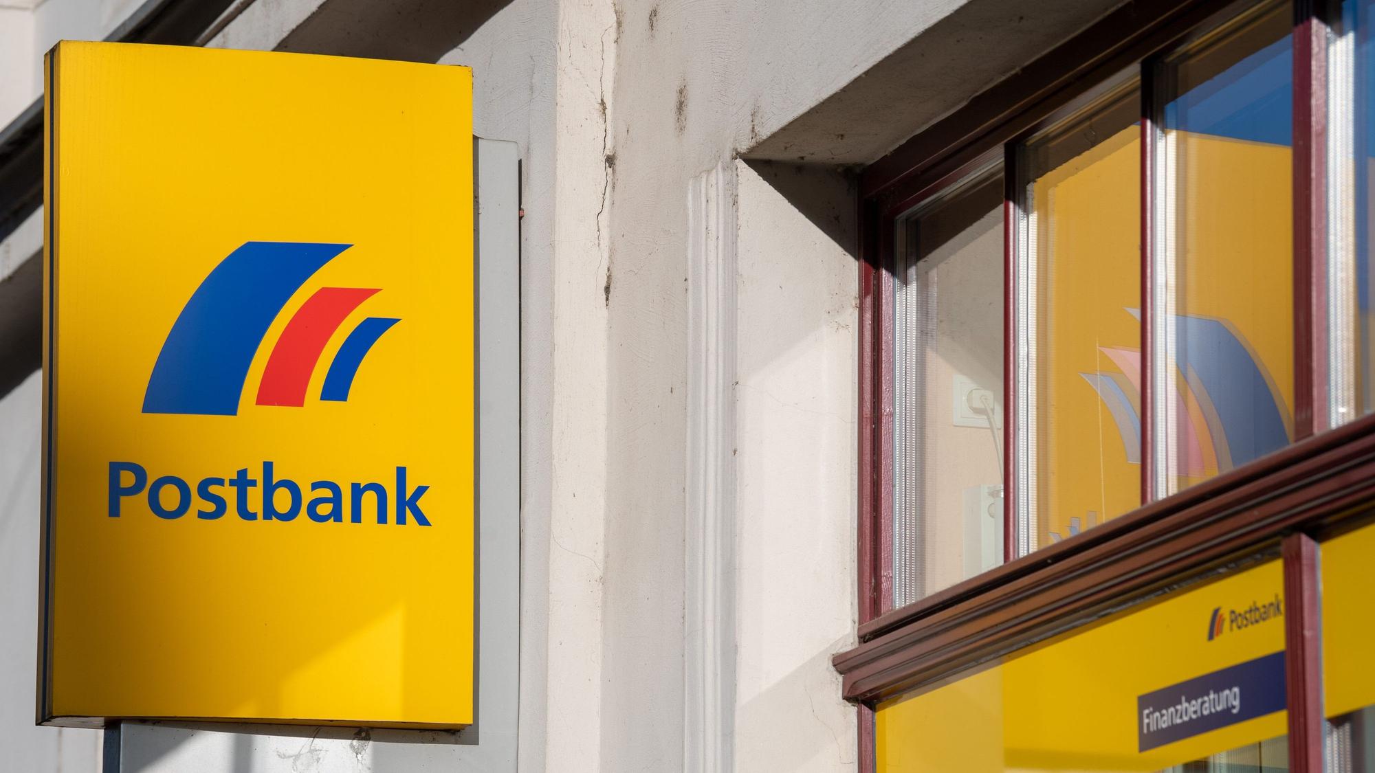 ARCHIV - 25.03.2019, Brandenburg an der Havel: Ein Schild mit dem Logo der Postbank ist an der Fassade einer Bankfiliale angebracht. Viele Bankkunden erledigen Bankgeschäfte am heimischen Computer. Die Deutsche Bank dünnt daher nun das Filialnetz der Tochter Postbank deutlich aus.(zu dpa "Deutsche Bank will fast die Hälfte der Postbank-Filialen schließen") Foto: Monika Skolimowska/dpa-Zentralbild/dpa +++ dpa-Bildfunk +++