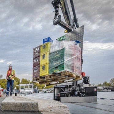HANDOUT - 16.10.2023, Frankreich, Paris: Von einem Schiff werden Getränke mit einem Kran auf einen Kai und von dort in einen Lieferwagen verladen.