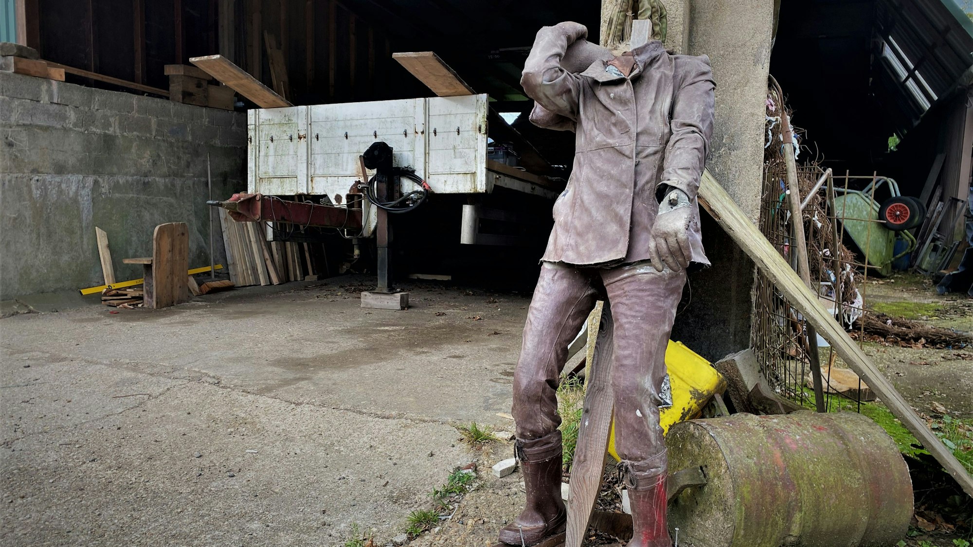 Auf einem Bauernhof steht eine Figur mit abgeschlagenem Kopf.