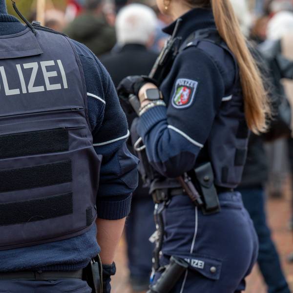 Zwei Polizisten stehen auf einem Weg.