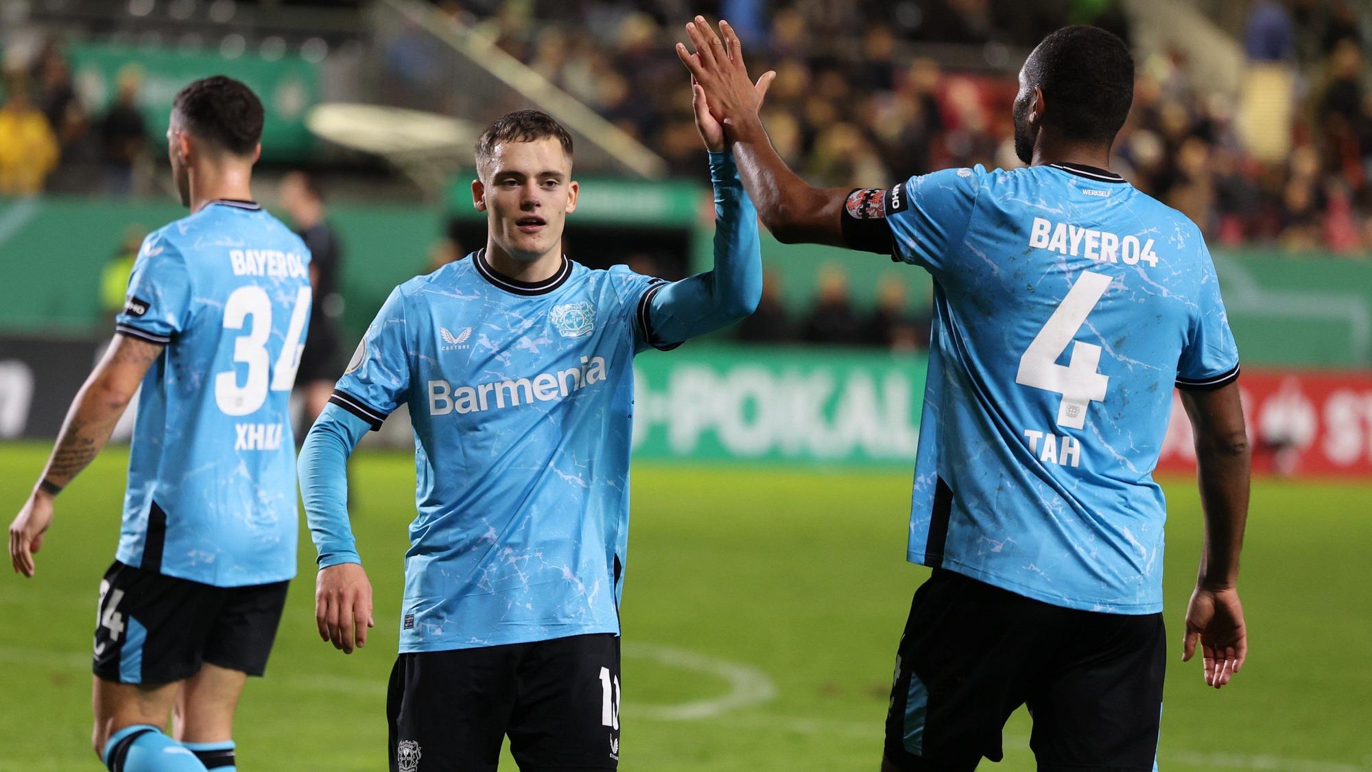 Leverkusens Florian Wirtz (l) und Jonathan Tah klatschen nach dem Spiel gegen den SV Sandhausen ab.