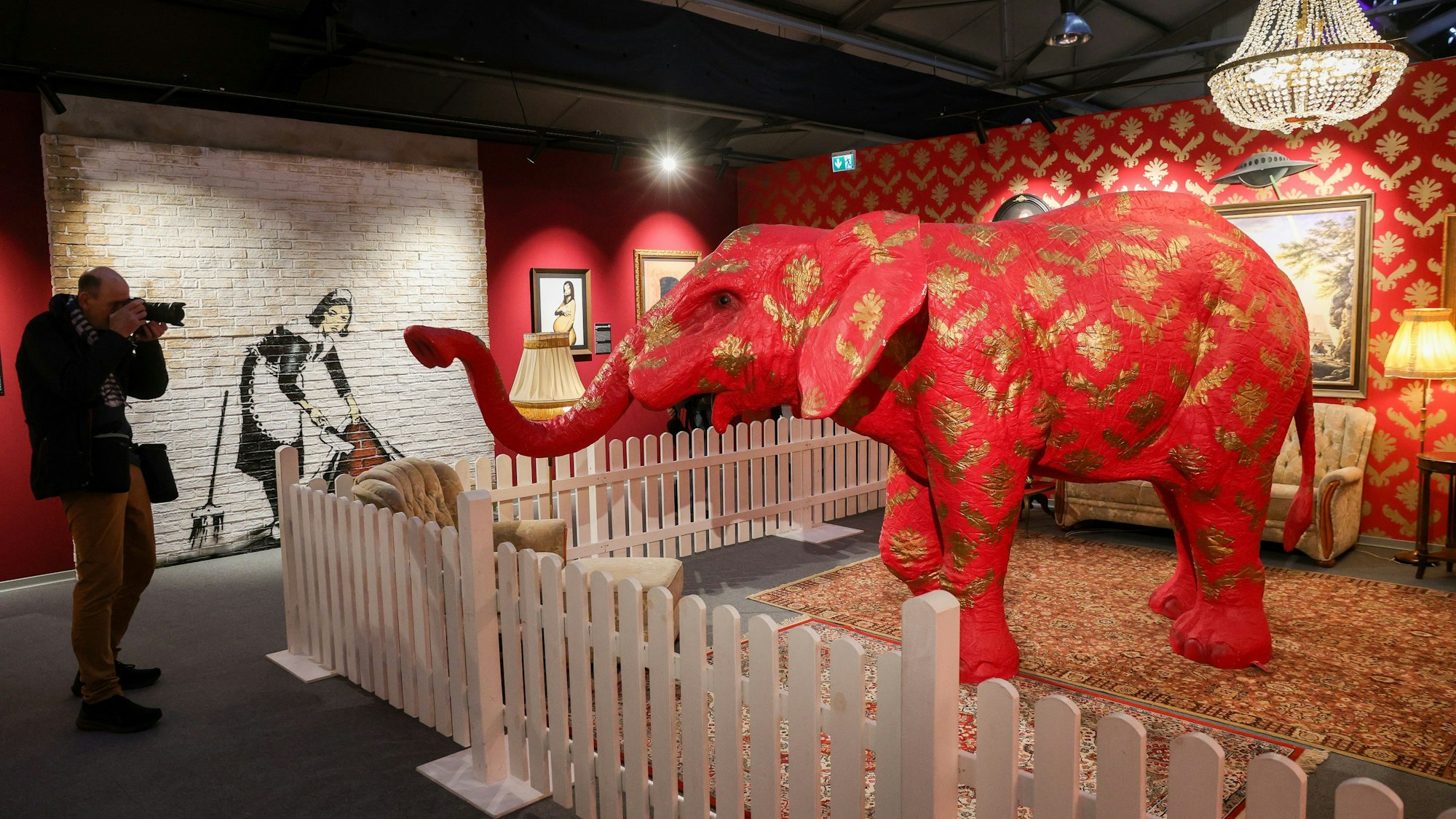 Ein roter Elefant streckt seinen Rüssel nach einem Fotografen aus.