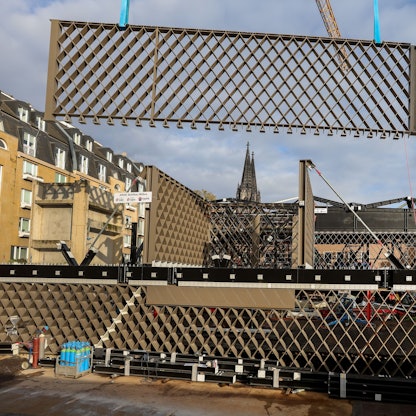 Ein Stahlbauteil in Rautenform hängt an einem Kran und wird eingesetzt.