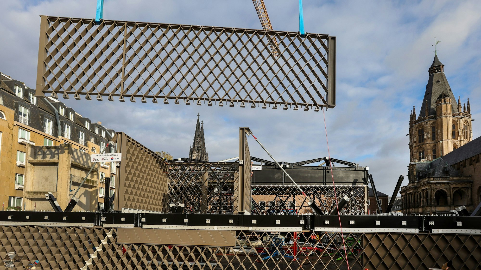 Ein Stahlbauteil in Rautenform hängt an einem Kran und wird eingesetzt.