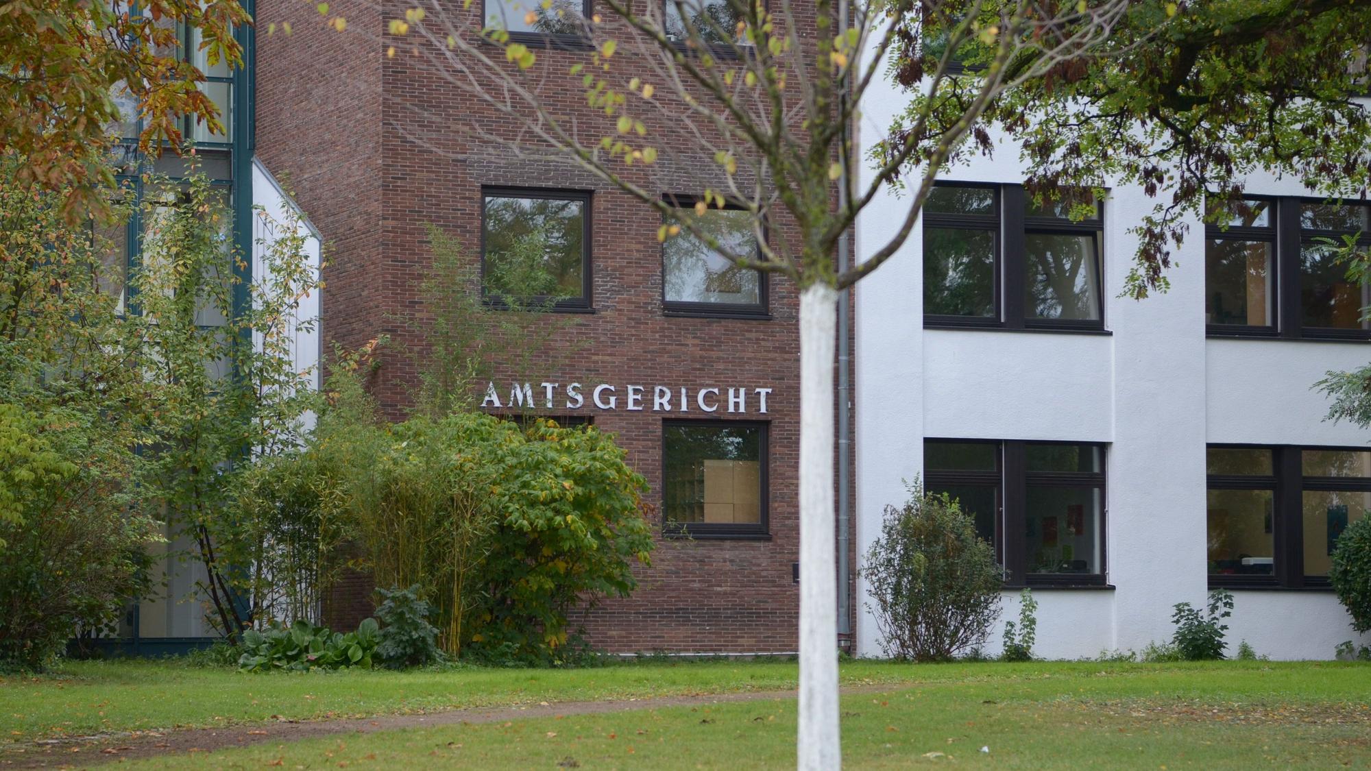 Die Fassade des Gerichtsgebäudes, im Vordergrund Bäume und Sträucher.