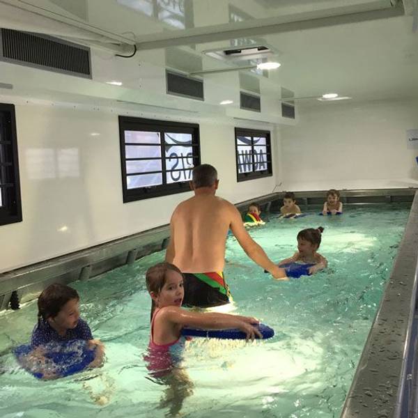 Kinder schwimmen in einem kleinen Becken in einem umgebauten Übersee-Container.