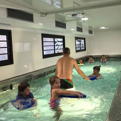Kinder schwimmen in einem kleinen Becken in einem umgebauten Übersee-Container.