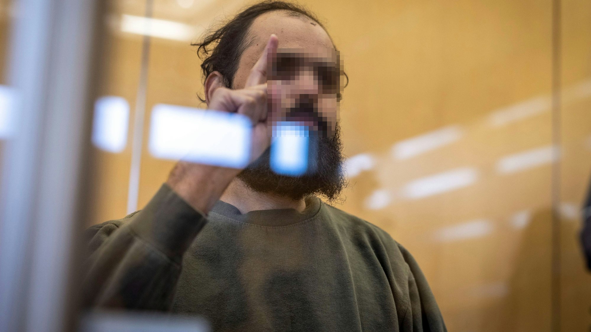 Terror-Prozess in Düsseldorf: Der Angeklagte Maan D. sitzt auf der Anklagebank hinter einer Glasscheibe, er zeigt dabei den Gruß der Kämpfer des IS. (Archivbild)