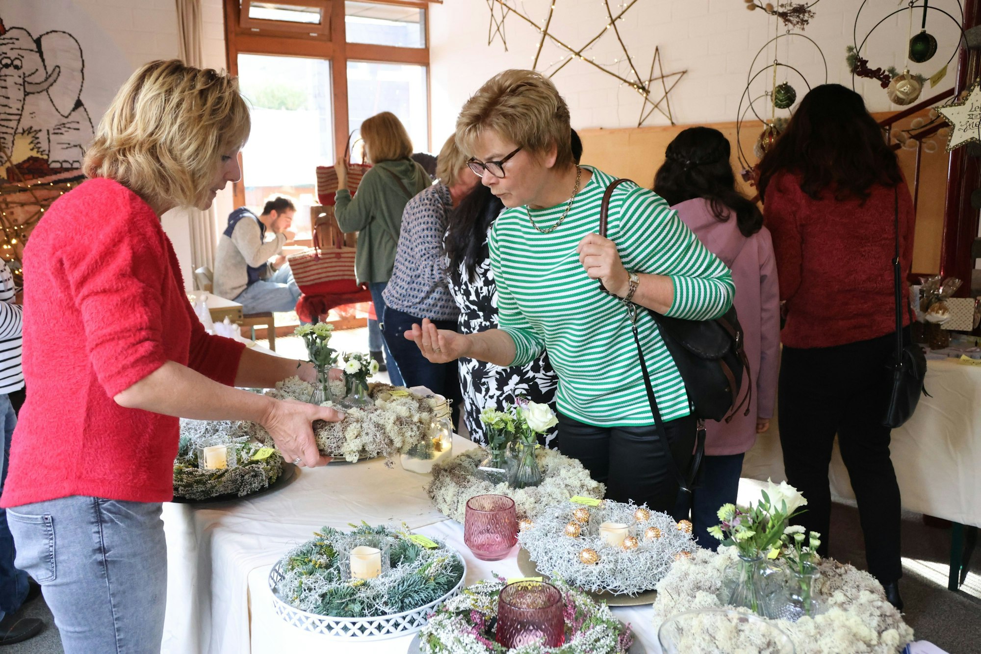Doris Hartmann steht am Stand von Kerstin Hupperich auf dem Waldbröler Missionsbasar Miba und interessiert sich für einen Adventskranz.