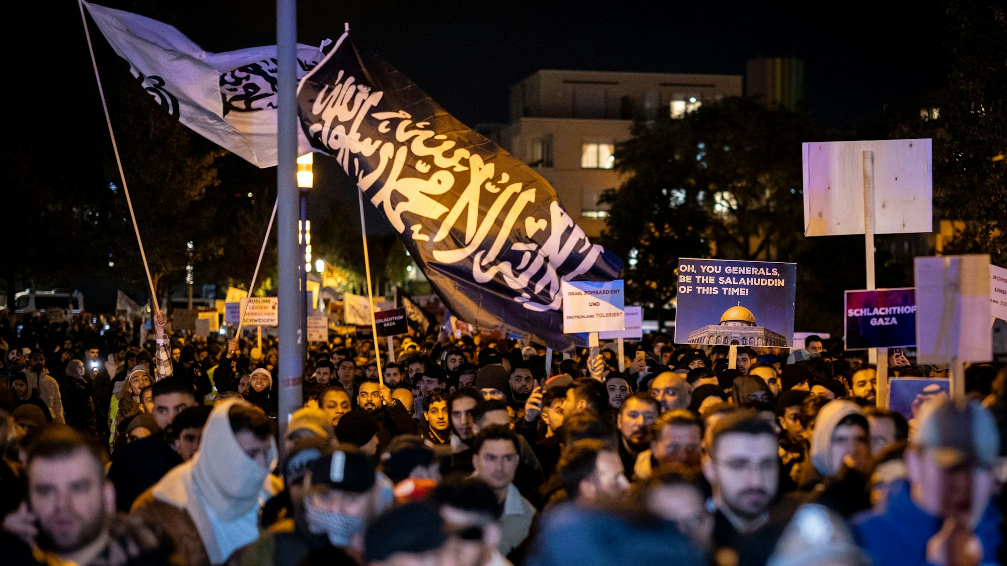 Essen: Eine Fahne mit arabischer Schrift weht bei der Kundgebung über einer Masse von Menschen.